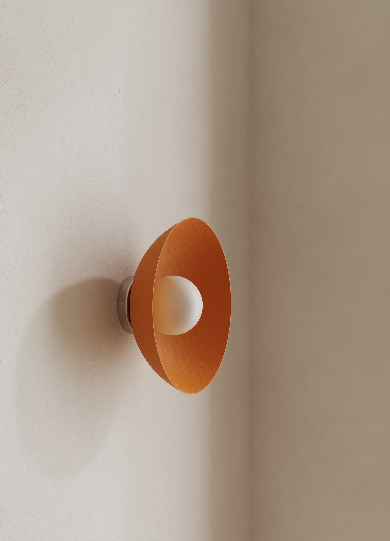 Wall-mounted light fixture with an orange shade on a neutral wall.