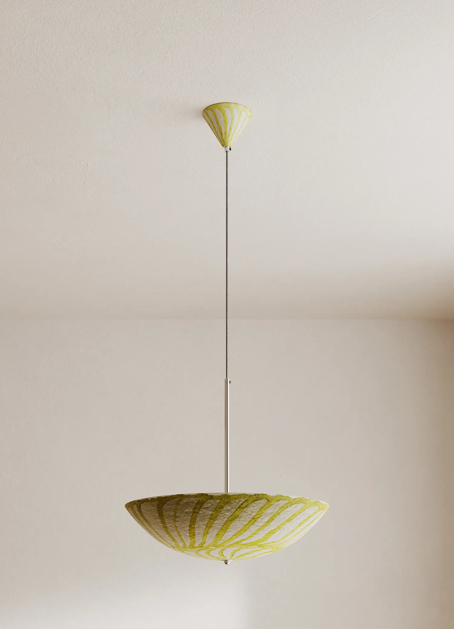 A modern pendant light fixture with a wide, shallow bowl shade and a matching ceiling canopy, both in a pale yellow and white striped pattern, suspended by a slim metal rod against a plain off-white wall.