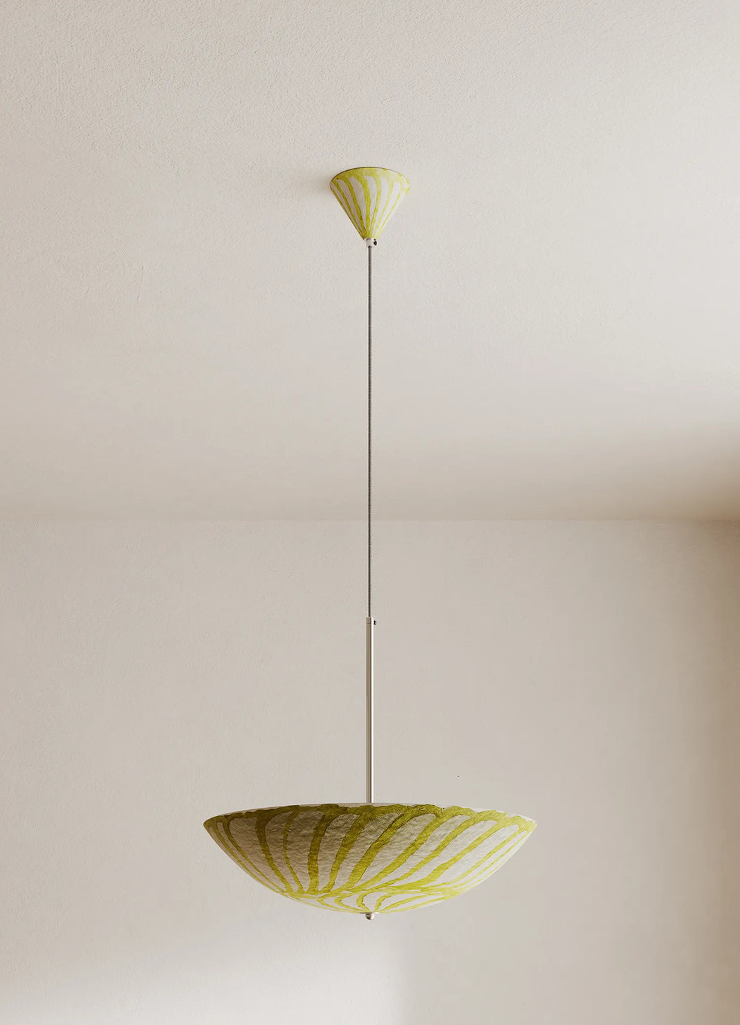 A modern pendant light fixture with a wide, shallow bowl shade and a matching ceiling canopy, both in a pale yellow and white striped pattern, suspended by a slim metal rod against a plain off-white wall.