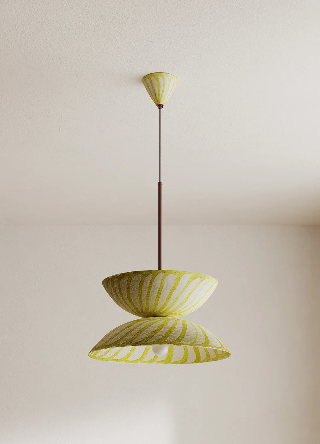 A modern pendant light fixture with two overlapping, shell-like shades in a yellow and white pattern, suspended by a thin dark metal rod from a matching ceiling canopy against a plain off-white wall.