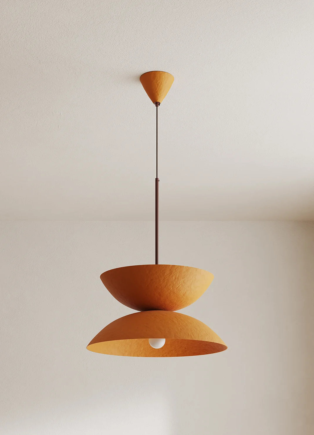 Orange pendant light hanging against a plain wall