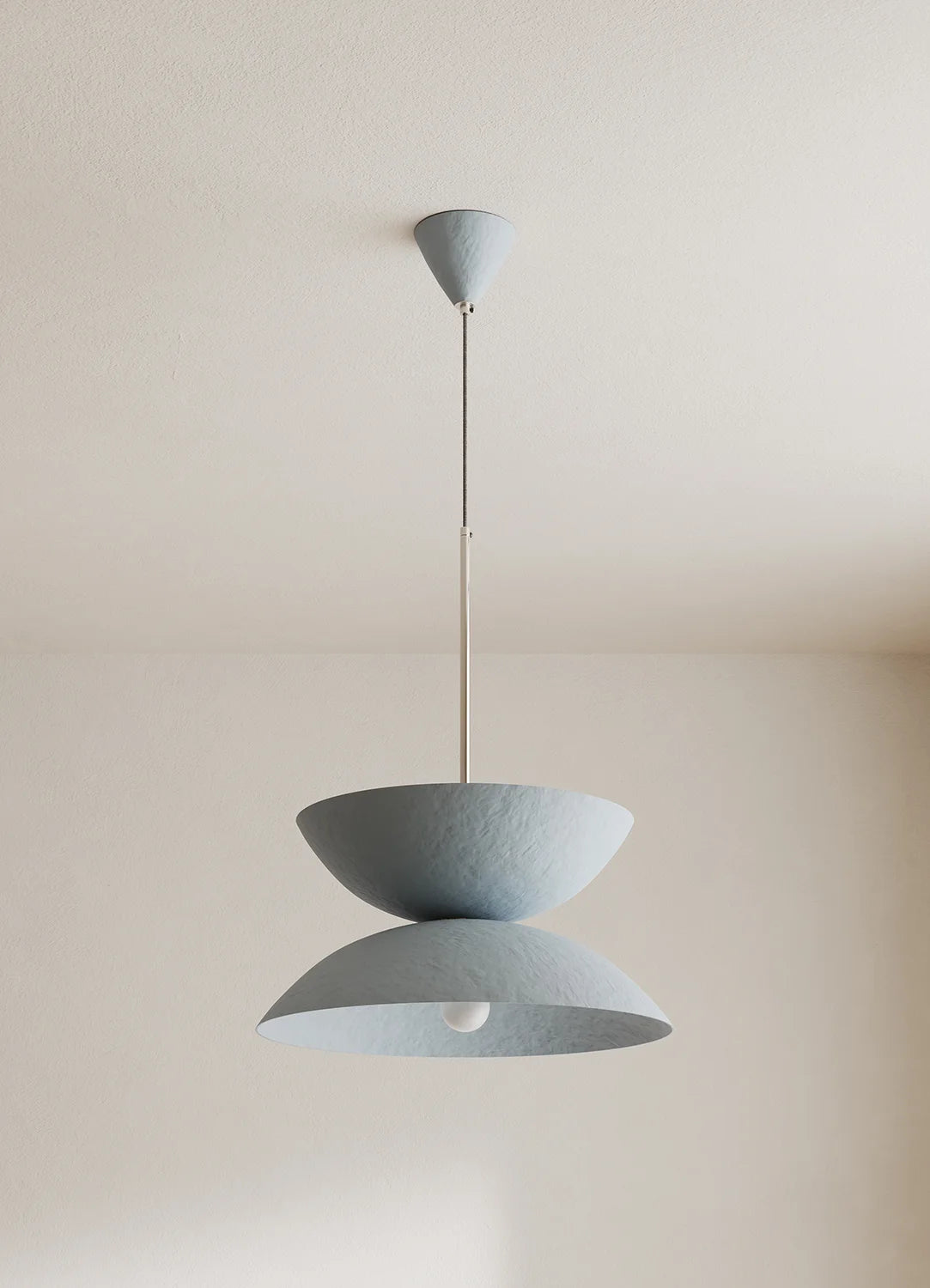 Light blue pendant lamp hanging against a plain wall