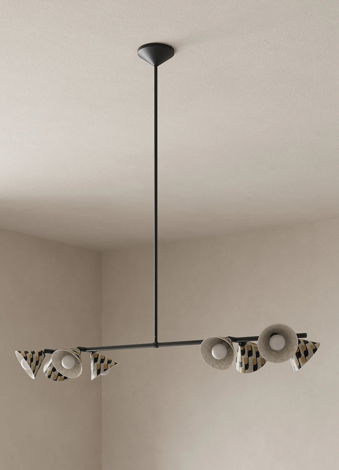 A modern multi-light linear chandelier with black metal hardware, featuring eight cylindrical shades with black-and-beige patterned stripes suspended from a ceiling in a minimalist beige room.