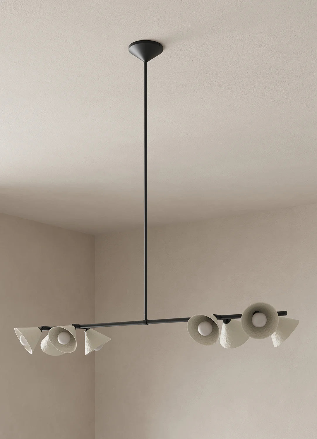 A modern linear chandelier with eight white paper pulp shades and a blackened bronze metal frame, suspended from a ceiling rose in a minimalist room with off-white walls.