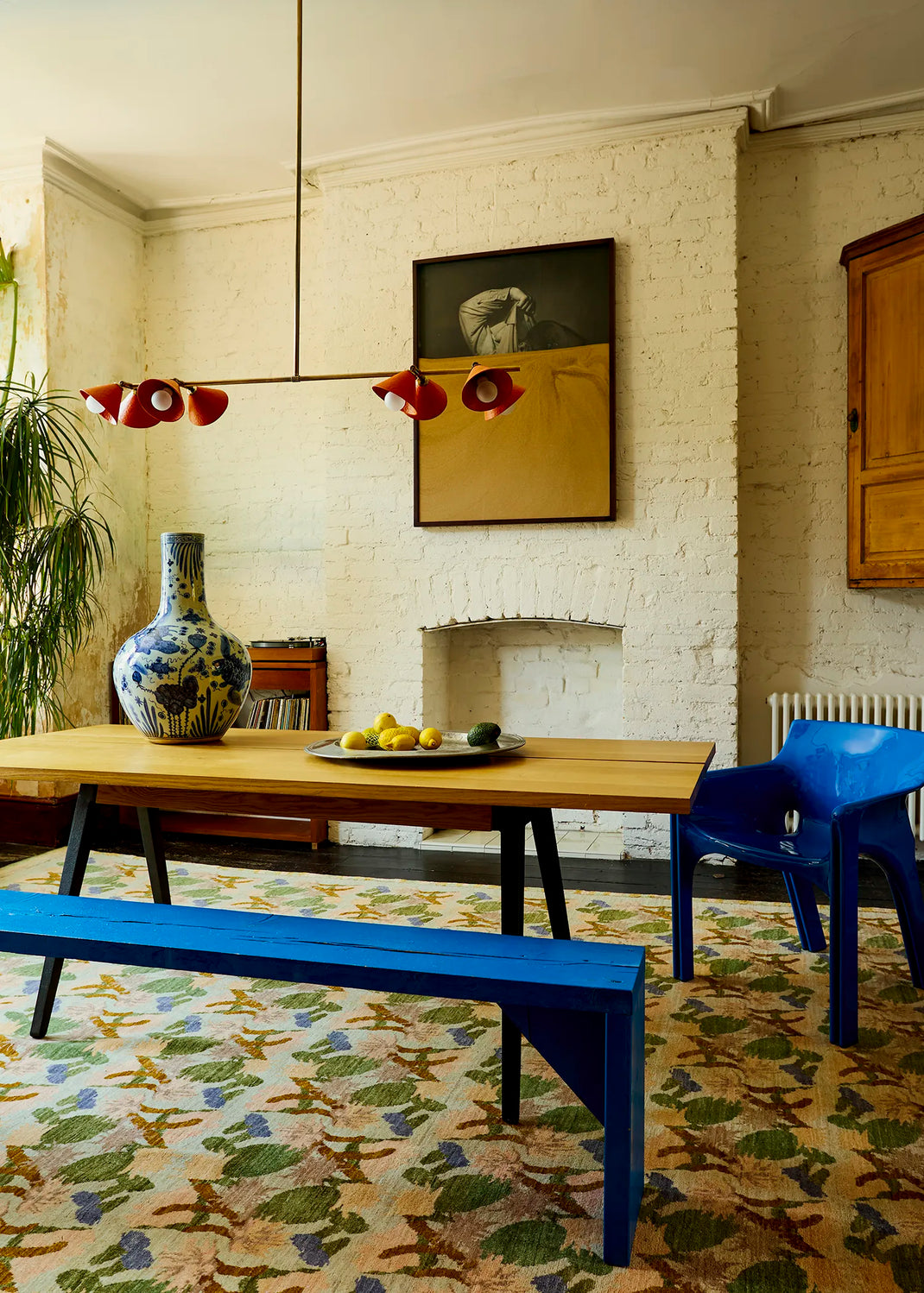 Palefire Studio Garland pendant light in antique brass with brick-red cone shades, suspended above a dining table in a colourful interior.