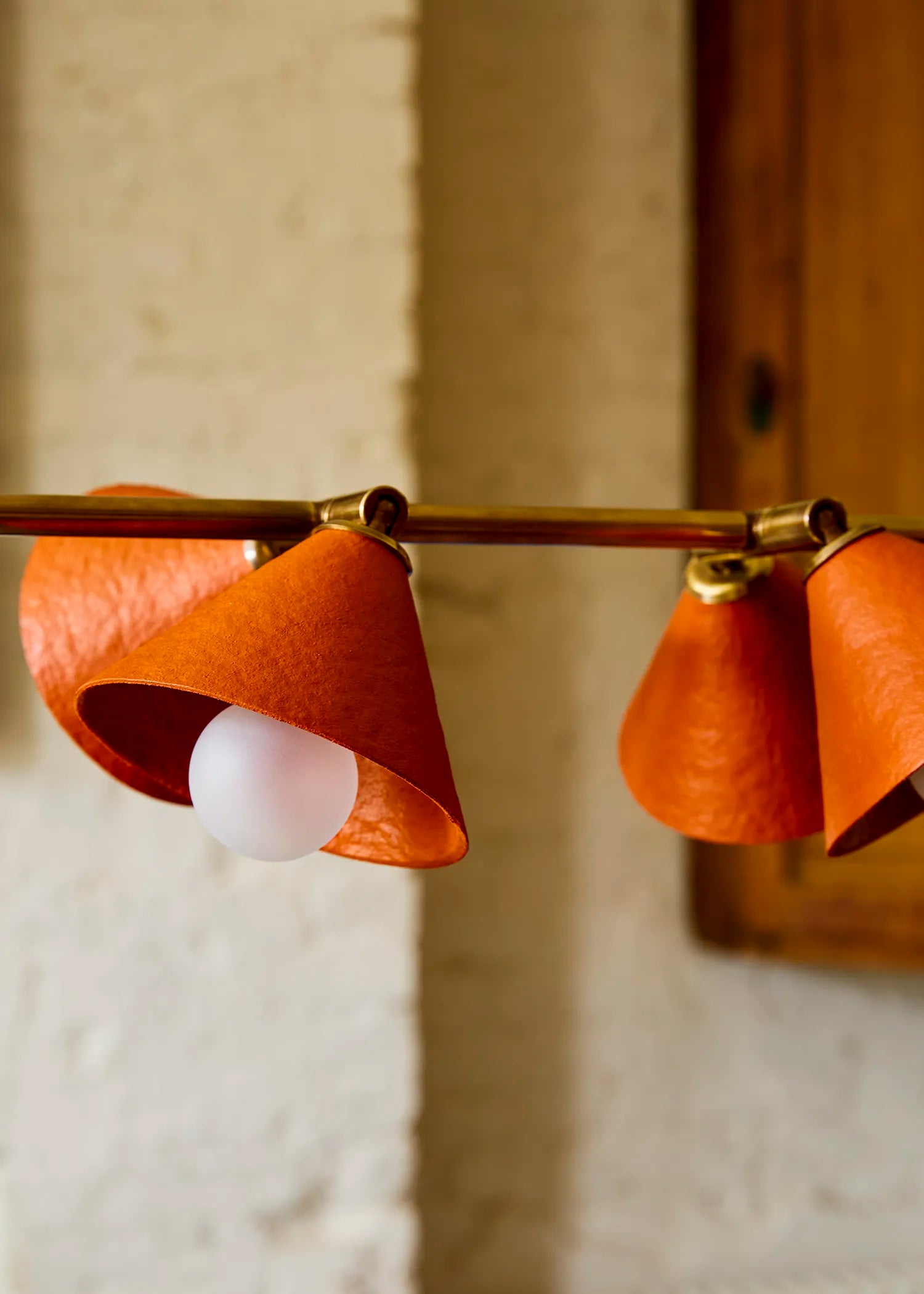 Close-up of Palefire Studio Garland pendant light in antique brass, showing its textured brick-red cone shades and diffused bulb covers.