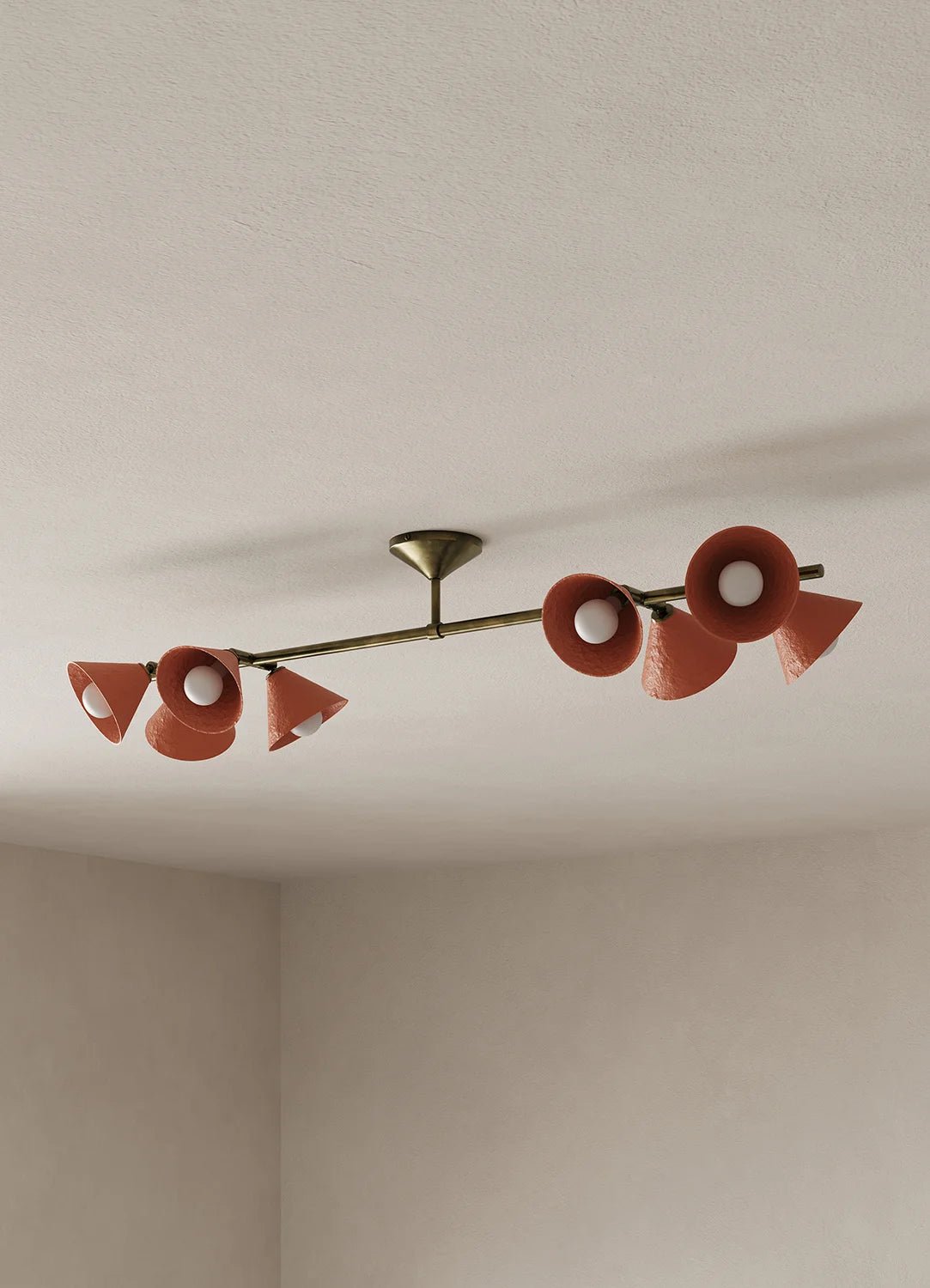 A mid-century modern linear ceiling light fixture with eight terracotta-colored cone-shaped shades and a brass-toned central bar, mounted on a textured off-white ceiling.