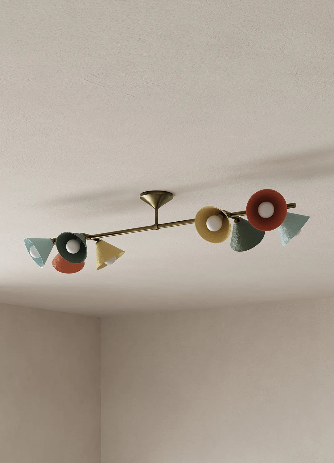 A mid-century modern ceiling light fixture with a brass-toned horizontal bar and multiple colorful shades in red, yellow, green, and blue, mounted on a textured off-white ceiling.