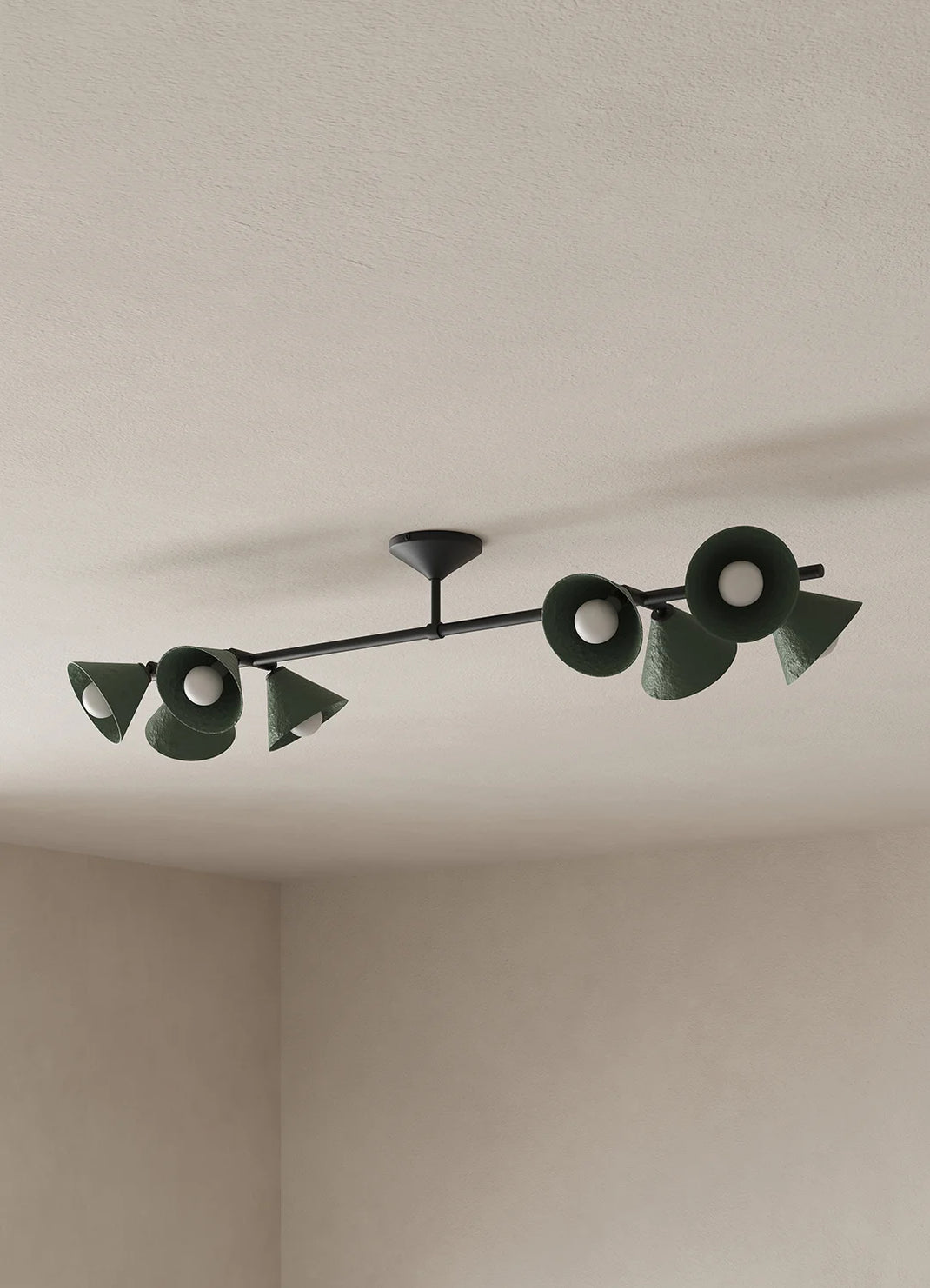 A modern ceiling-mounted light fixture with a black horizontal bar and multiple dark green cone-shaped shades, shown installed on a textured off-white ceiling in a room corner.