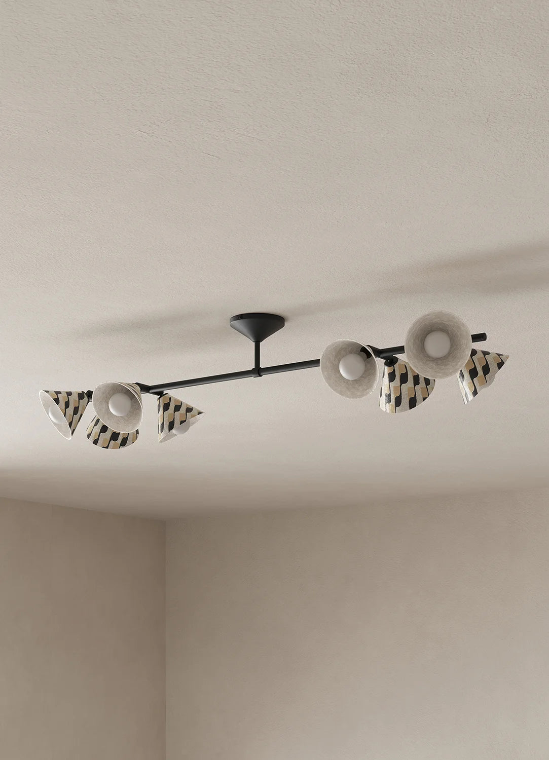 A modern ceiling-mounted light fixture with a black horizontal bar and multiple white and black patterned shades, installed on a textured off-white ceiling in a minimalist room.