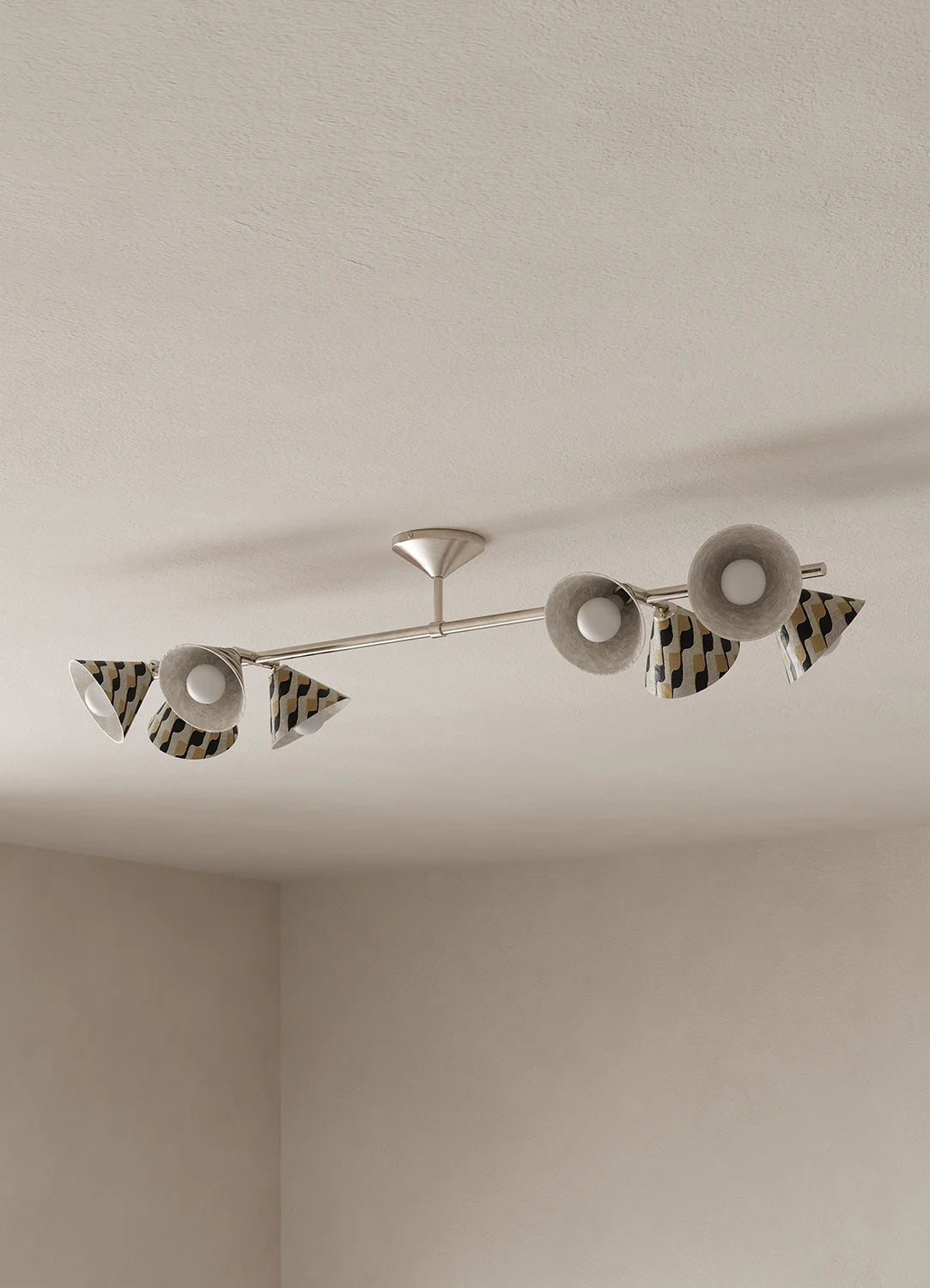 A modern ceiling-mounted light fixture with a slim silver metal bar and multiple shades with a black and beige diagonal stripe pattern, installed on a textured off-white ceiling.
