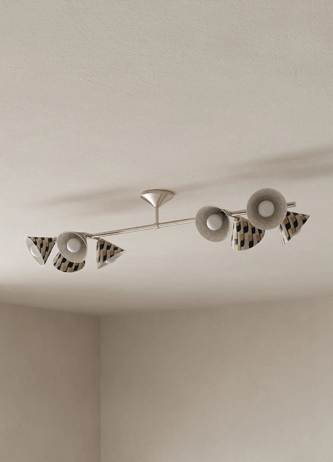 A modern ceiling-mounted light fixture with a slim silver metal bar and multiple shades with a black and beige diagonal stripe pattern, installed on a textured off-white ceiling.