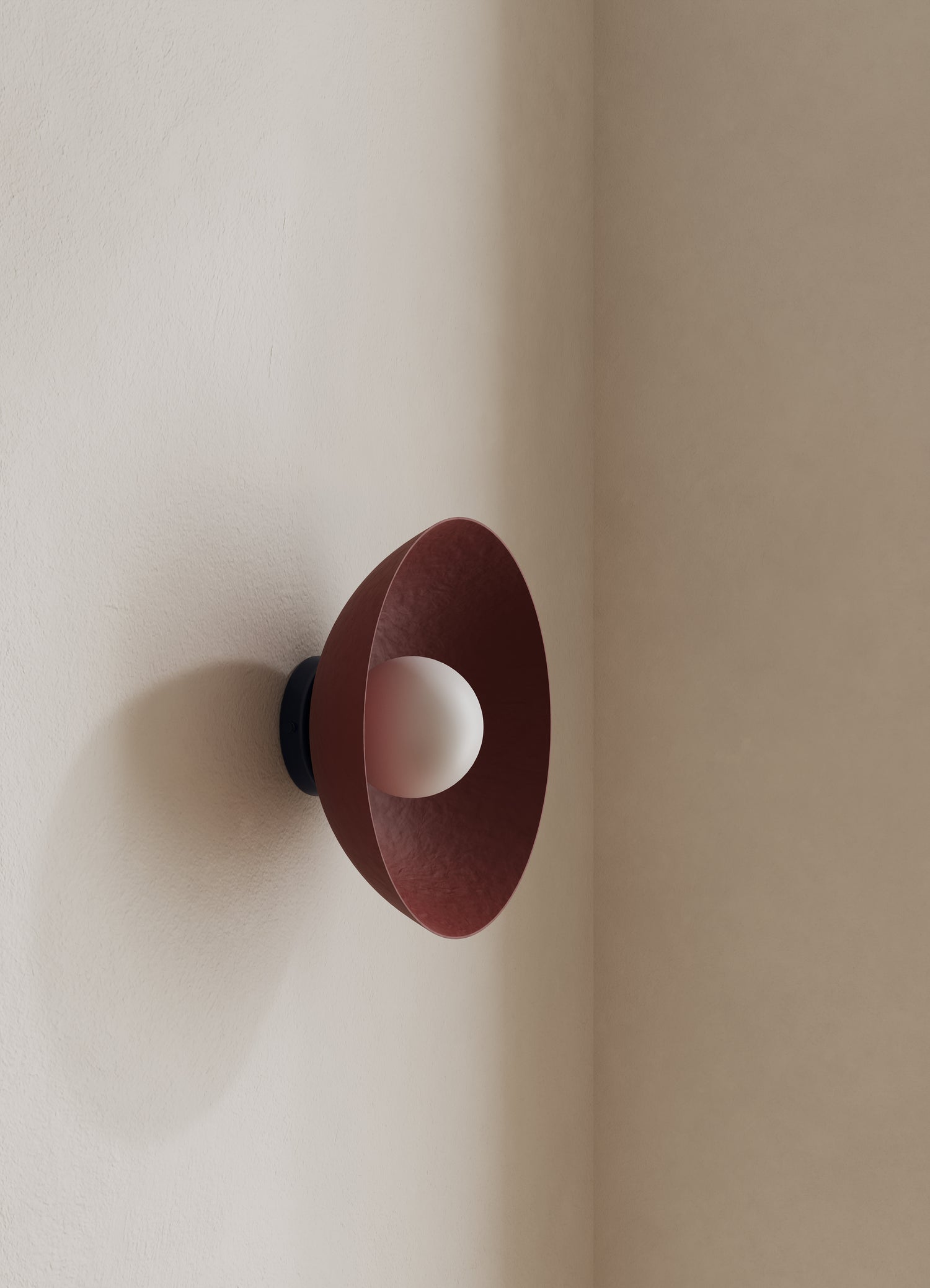Wall-mounted light fixture with a burgundy shade on a neutral wall.