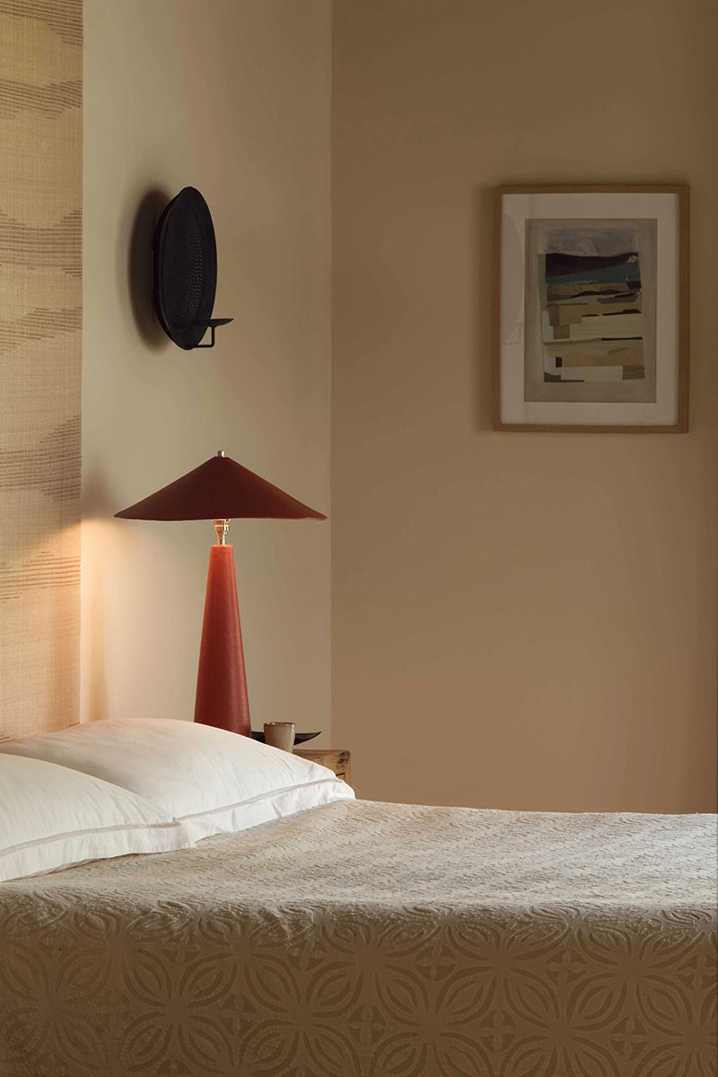 Orange table lamp beside a bed.