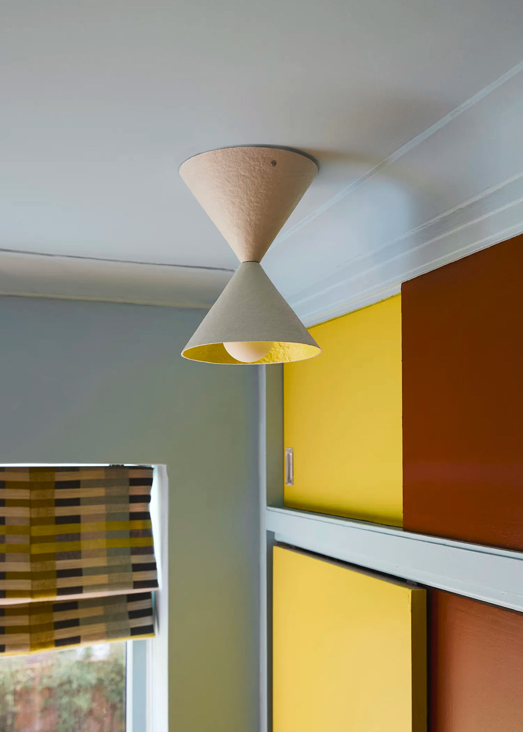 Ceiling light fixture in a room with colorful walls and a window.