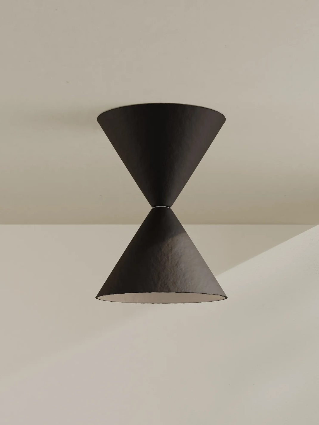 A modern brown-black cone-shaped ceiling mount with a textured finish, set against a minimalist beige wall and ceiling.