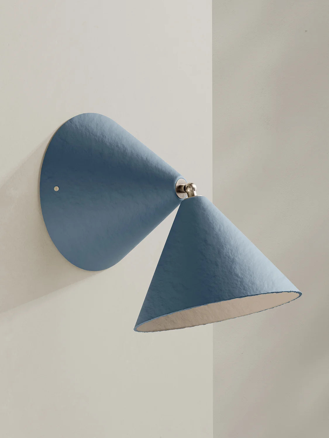 A modern blue wall sconce with a conical shade and a circular backplate, mounted on a light beige wall.