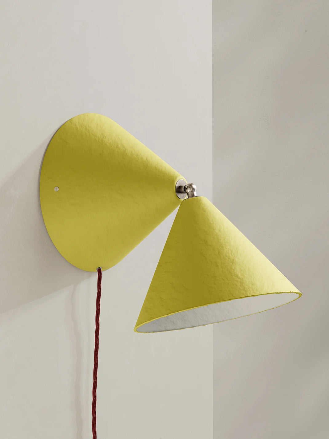 Modern wall lamp with two yellow cone-shaped shades on a neutral background