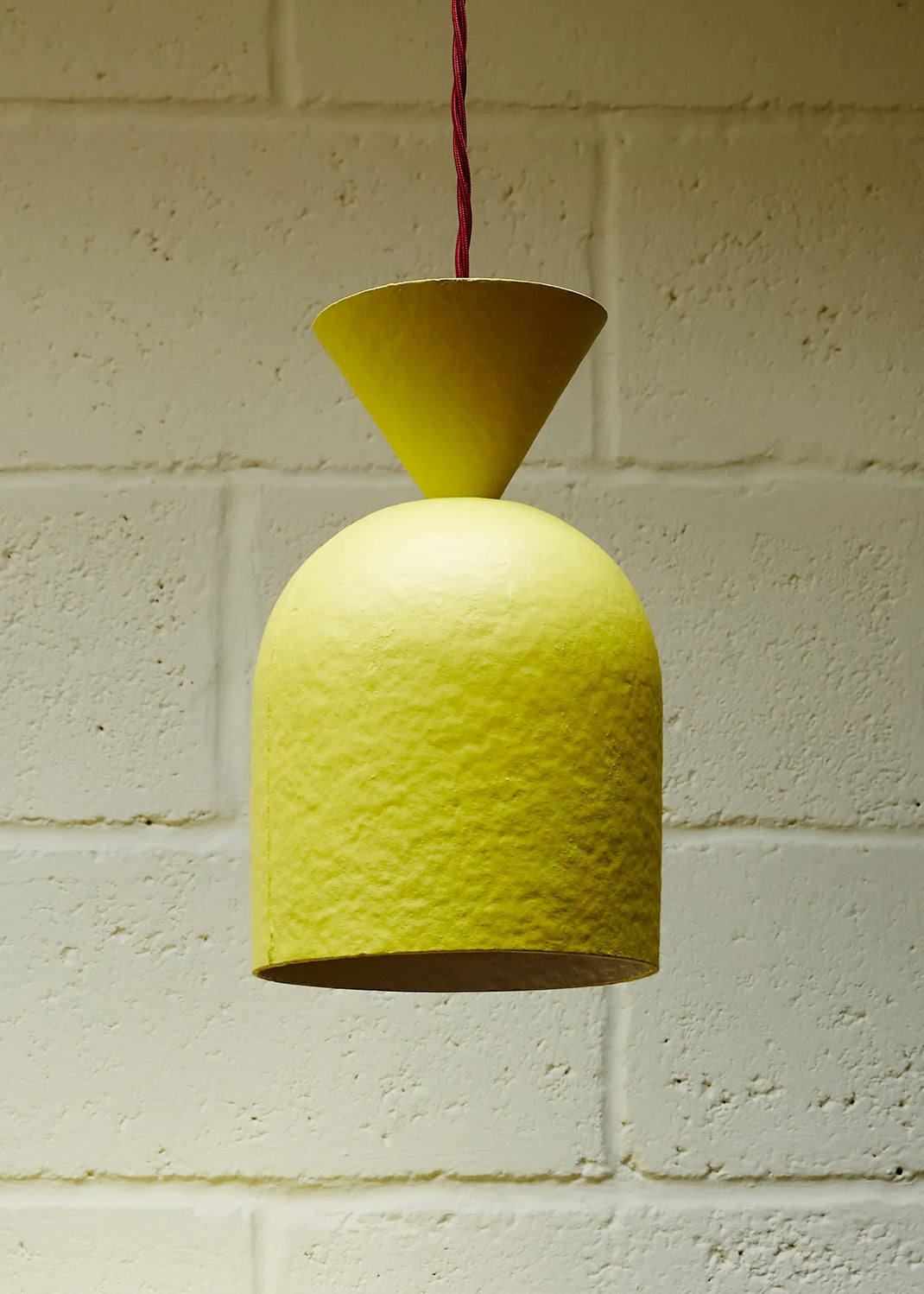Yellow pendant lamp hanging against a white brick wall