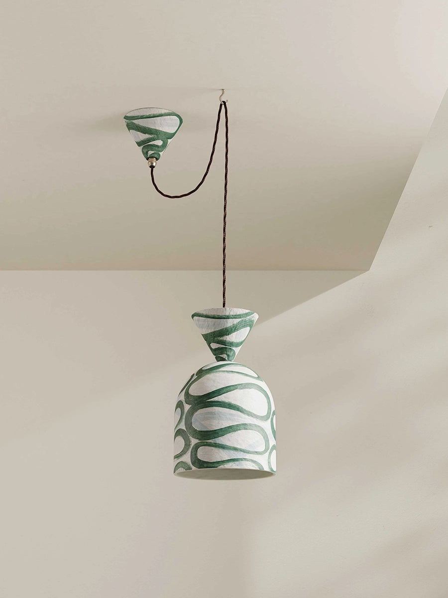 Green and white patterned pendant light hanging against a neutral background