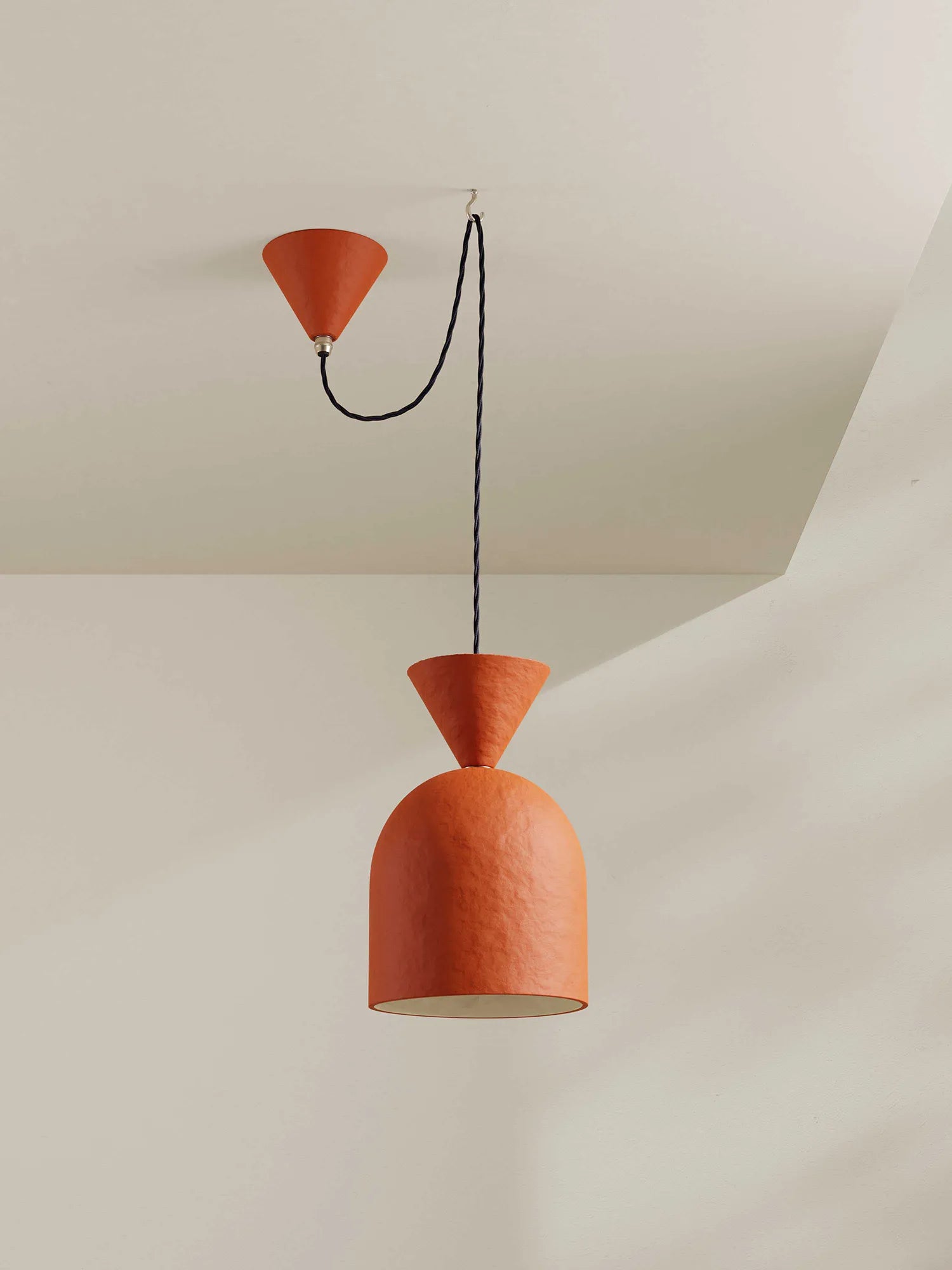 Terracotta pendant light with midnight blue cord hanging against a neutral background