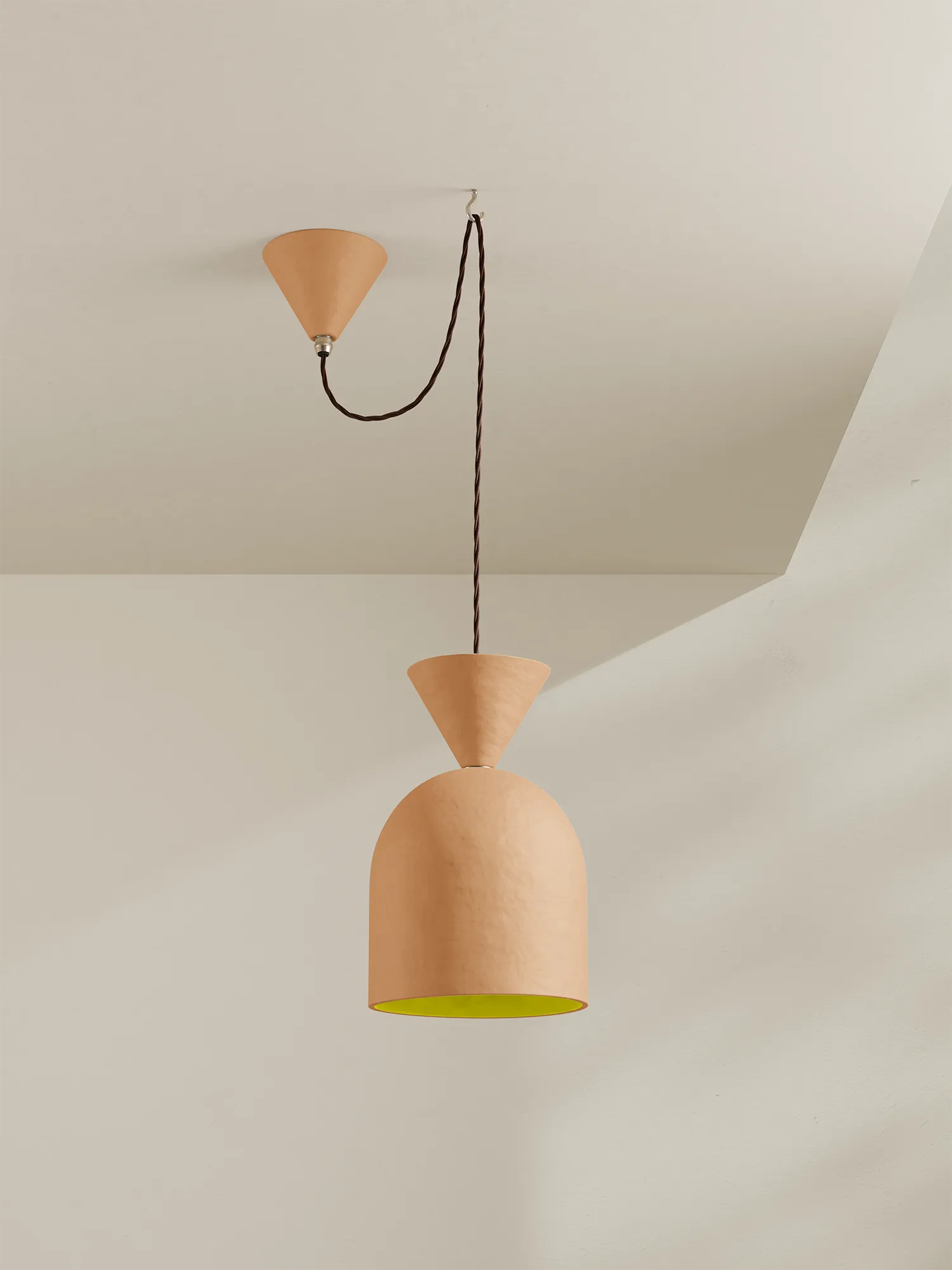 A peach-coloured pendant light with a citrus interior on a neutral background
