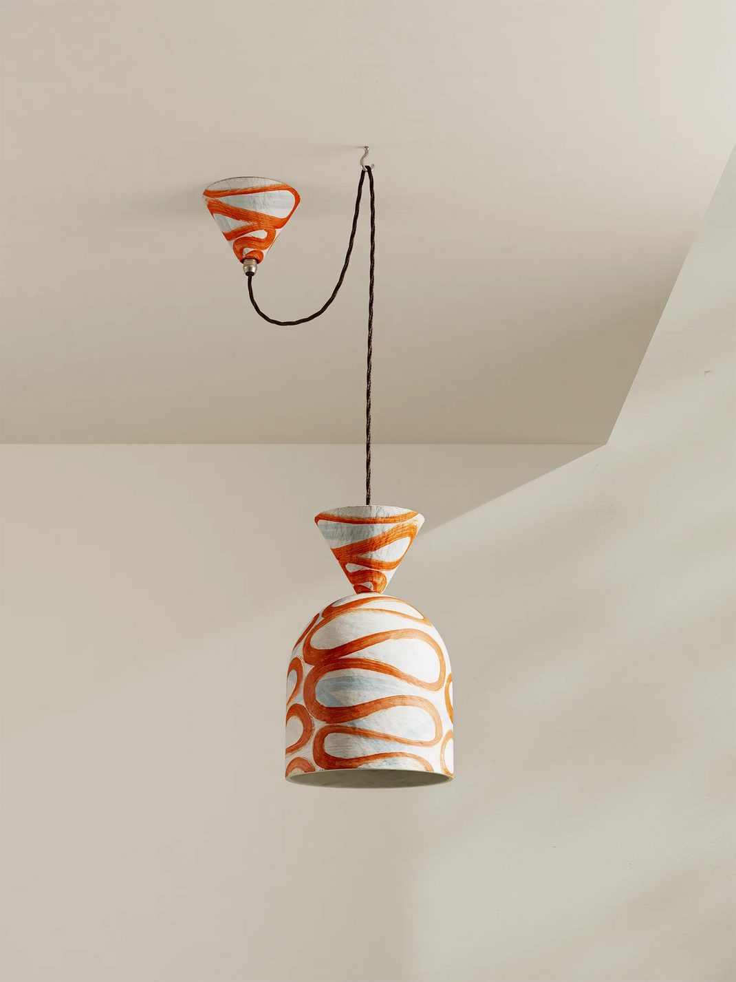 A paper-pilp pendant light with brick-orange and white design on a neutral background