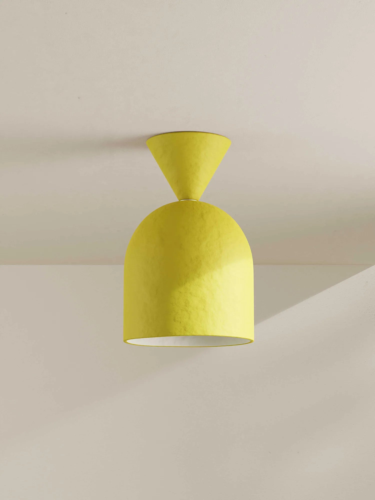 A modern pendant light with a textured yellow shade featuring a flared conical neck and a rounded dome-shaped body, shown hanging against a neutral off-white wall.