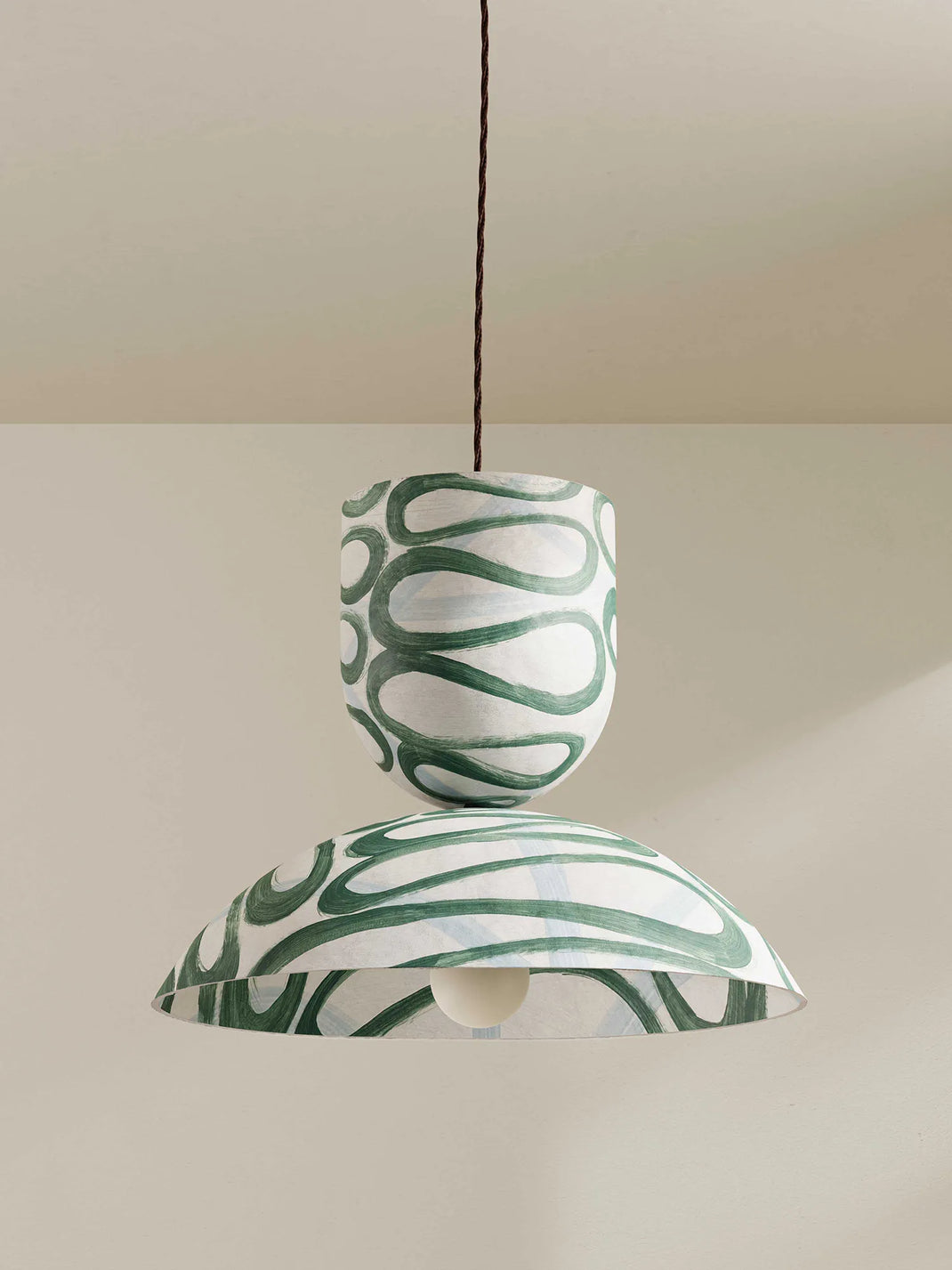 Green and white patterned pendant light on a neutral background