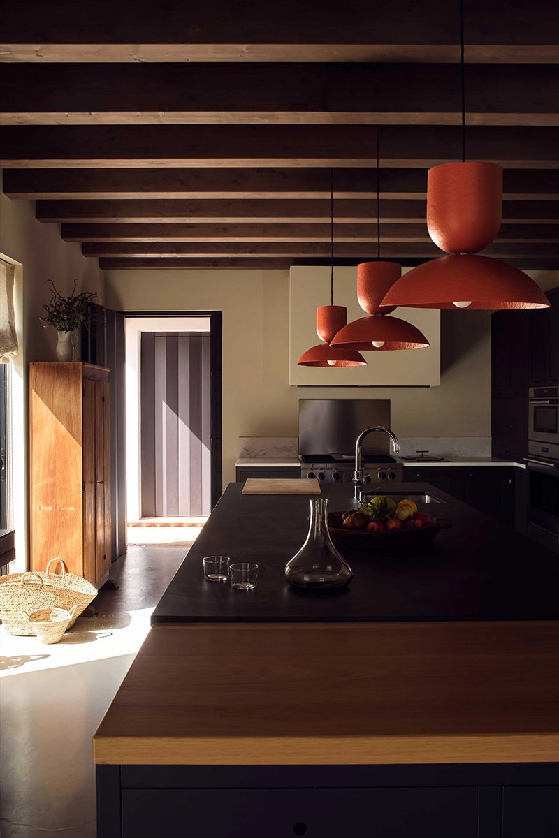 Modern kitchen with wooden island, red pendant lights, and a view of the outdoors.
