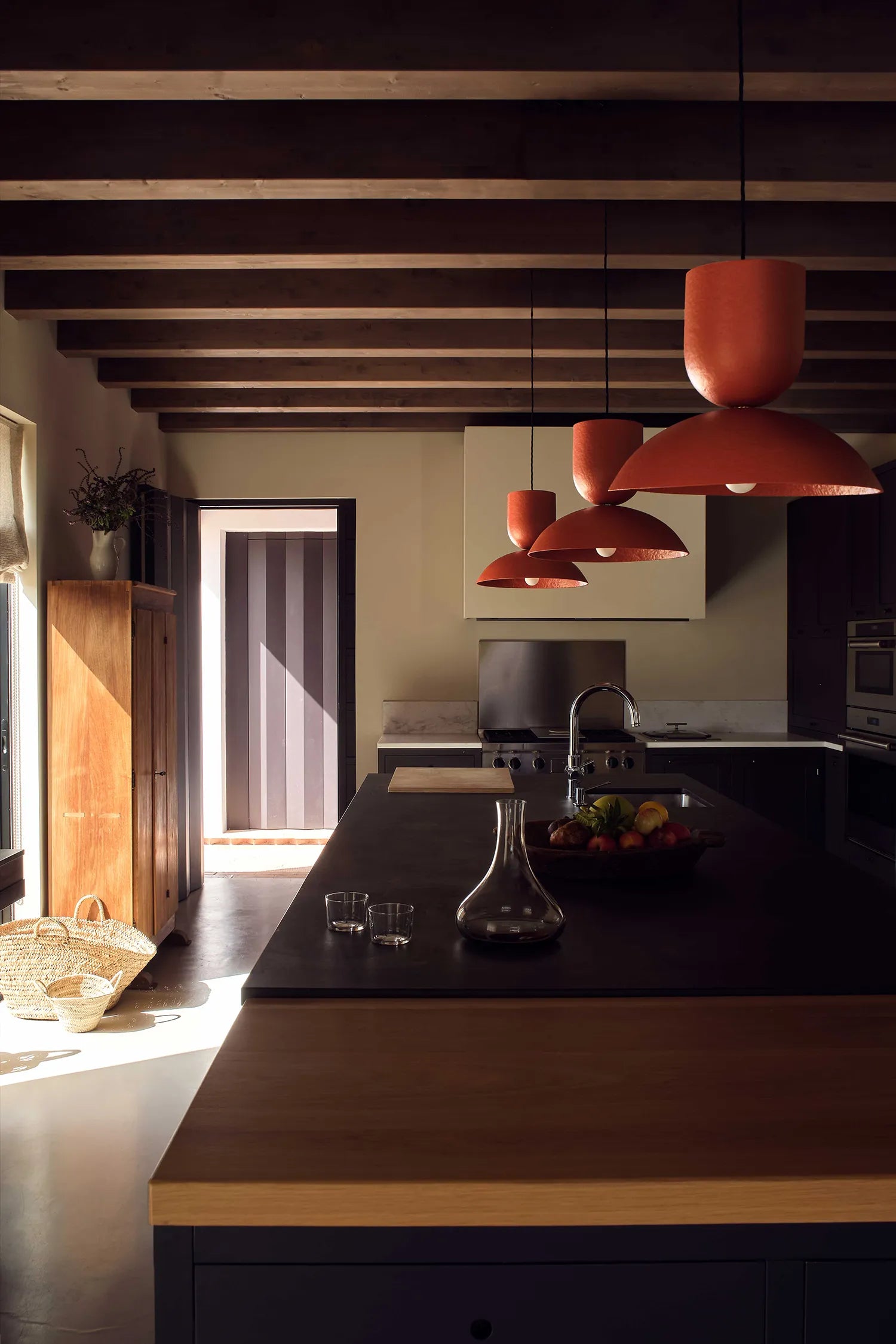 Modern kitchen with wooden island, red pendant lights, and a view of the outdoors.