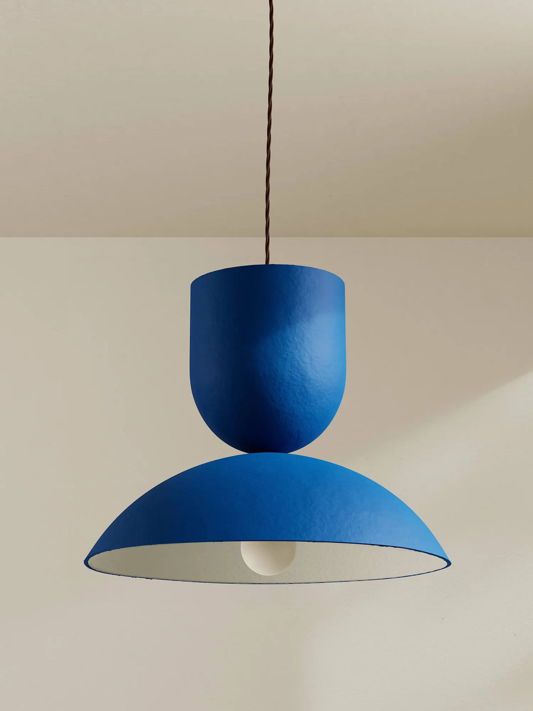 Blue pendant light hanging against a beige wall