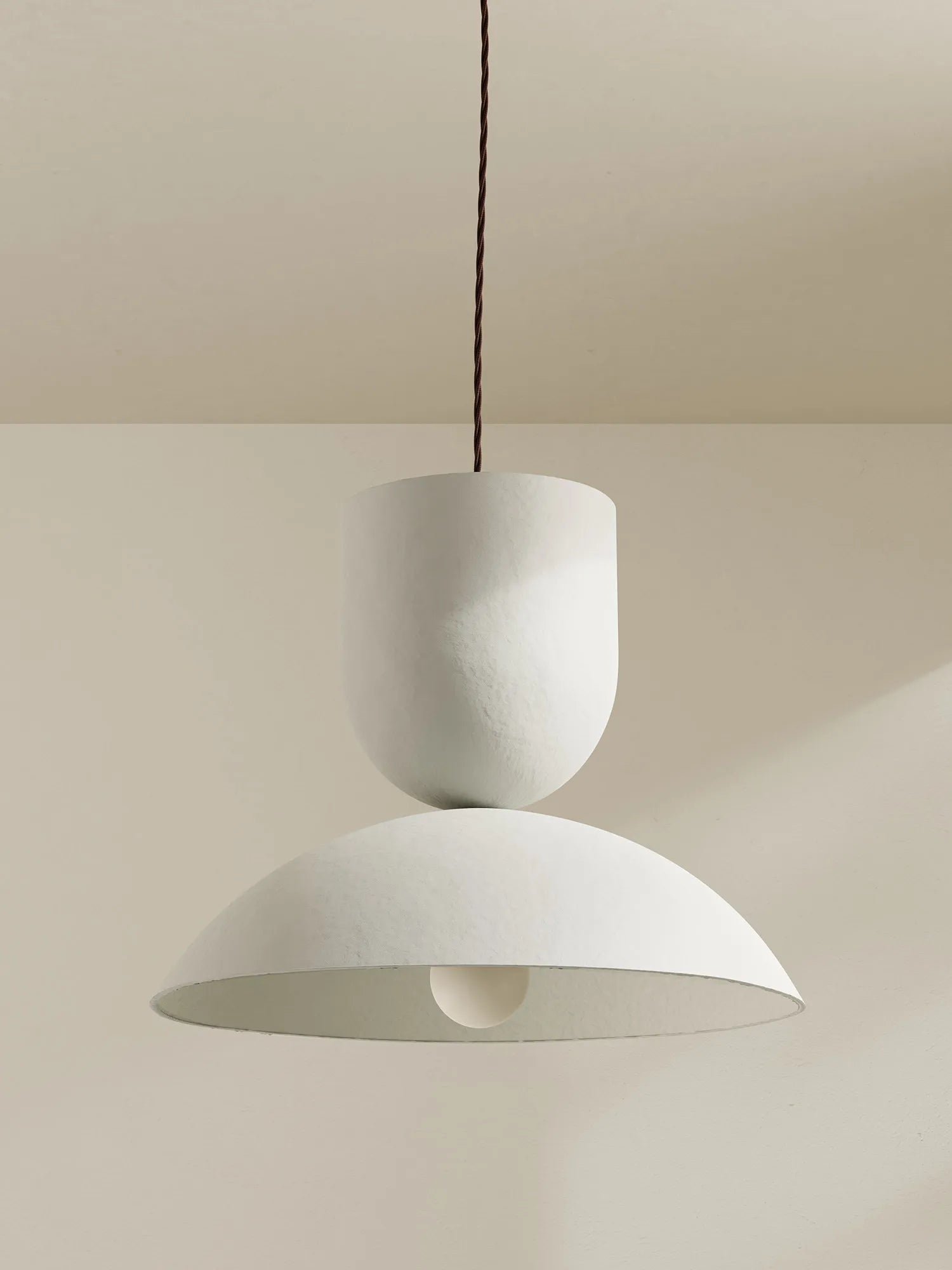 A white pendant with a textured finish hangs against a neutral background.