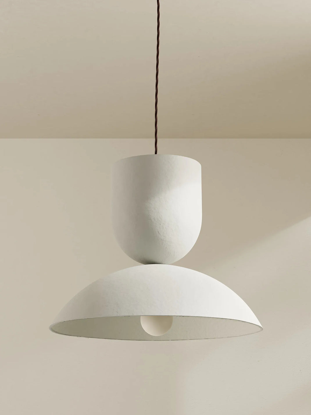 A white pendant with a textured finish hangs against a neutral background.