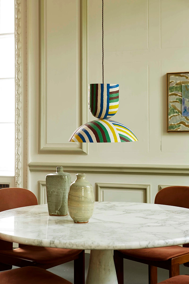 Colorful pendant light hanging above a marble dining table with ceramic vases.