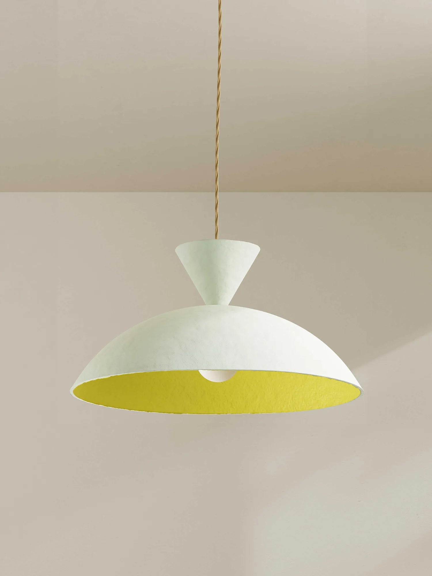 A modern pendant light with a wide, shallow dome-shaped shade featuring a textured off-white exterior and a bright yellow interior, suspended by a thin beige cord against a minimalist beige wall and ceiling.