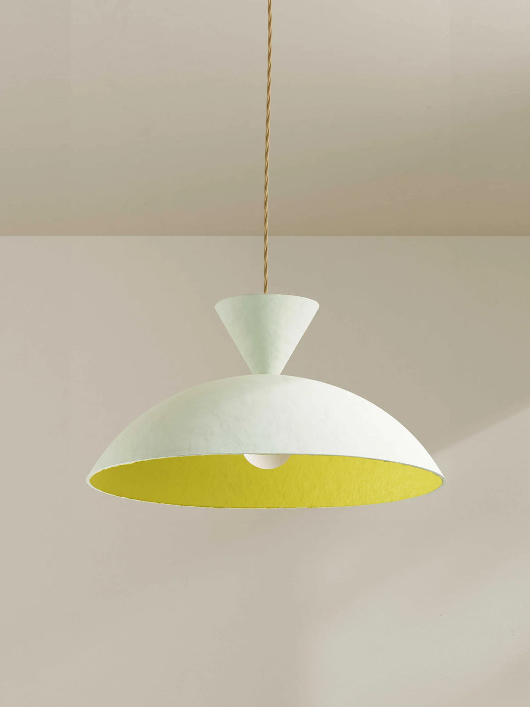 A modern pendant light with a wide, shallow dome-shaped shade featuring a textured off-white exterior and a bright yellow interior, suspended by a thin beige cord against a minimalist beige wall and ceiling.