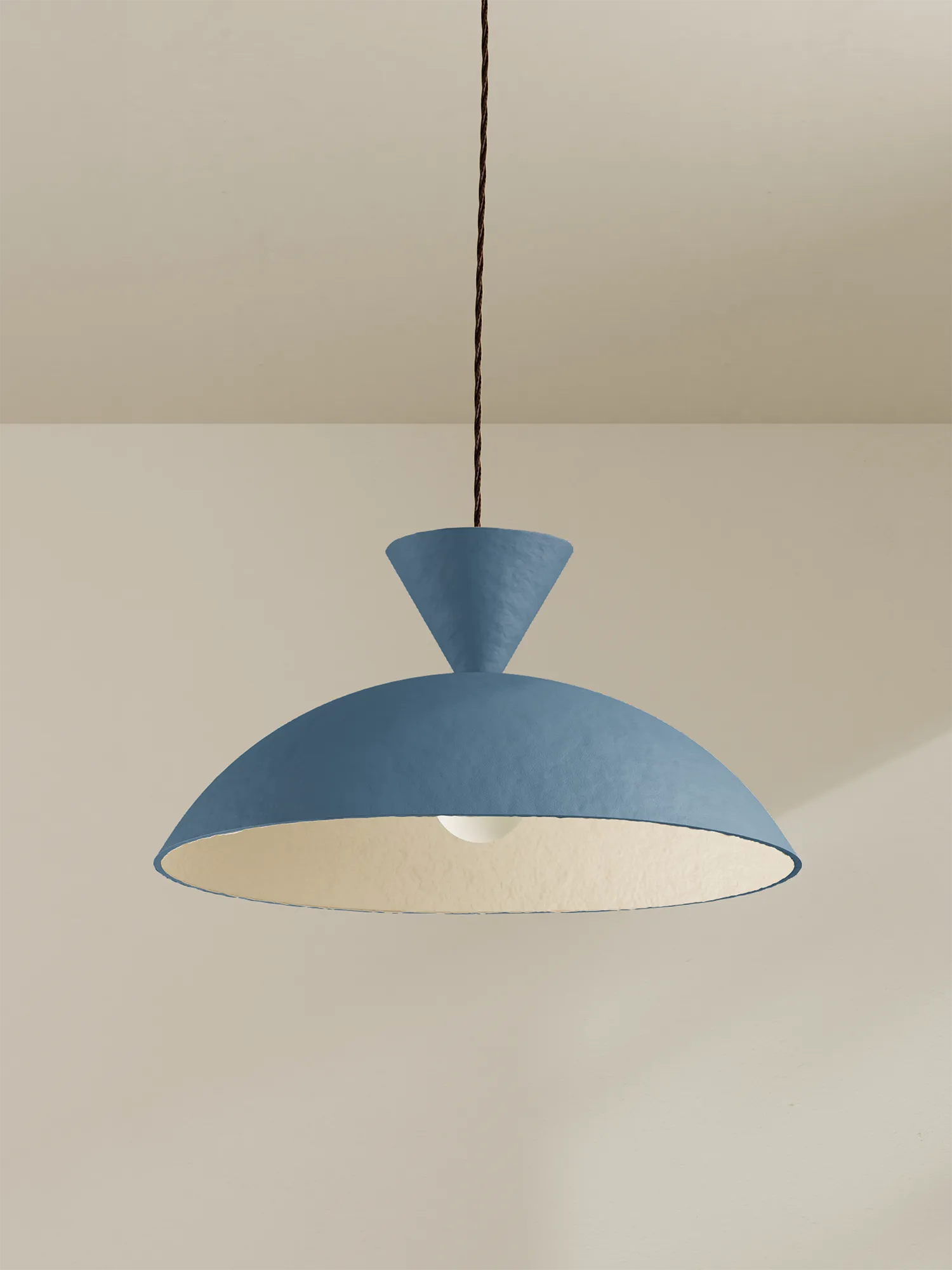 Blue pendant light hanging against a beige wall