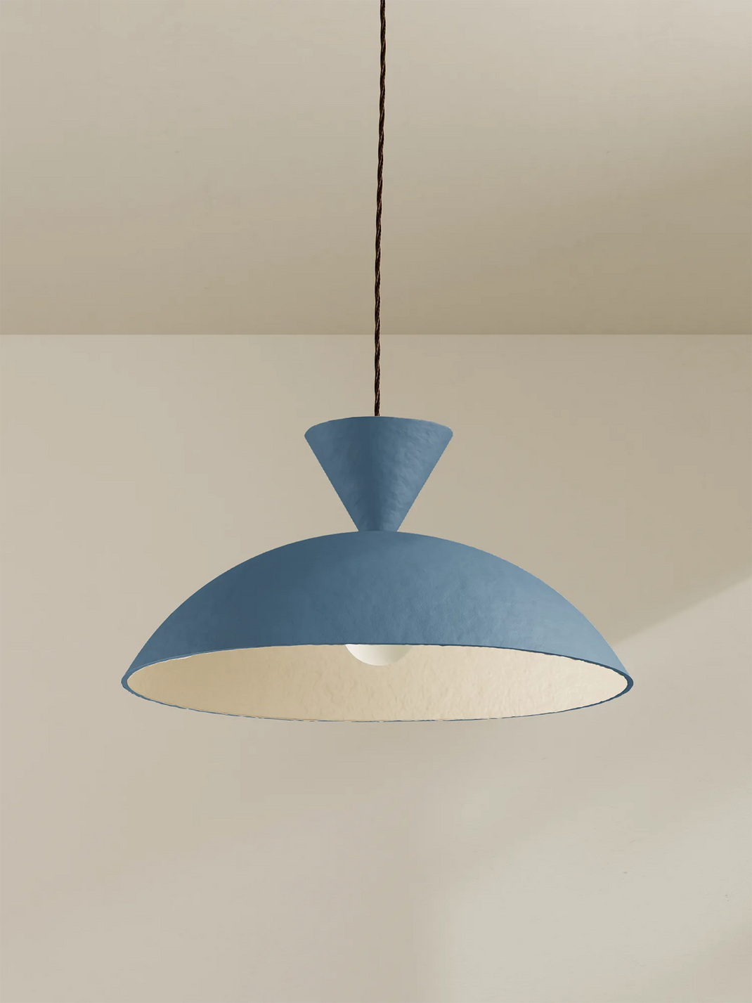 Blue pendant light hanging against a beige wall