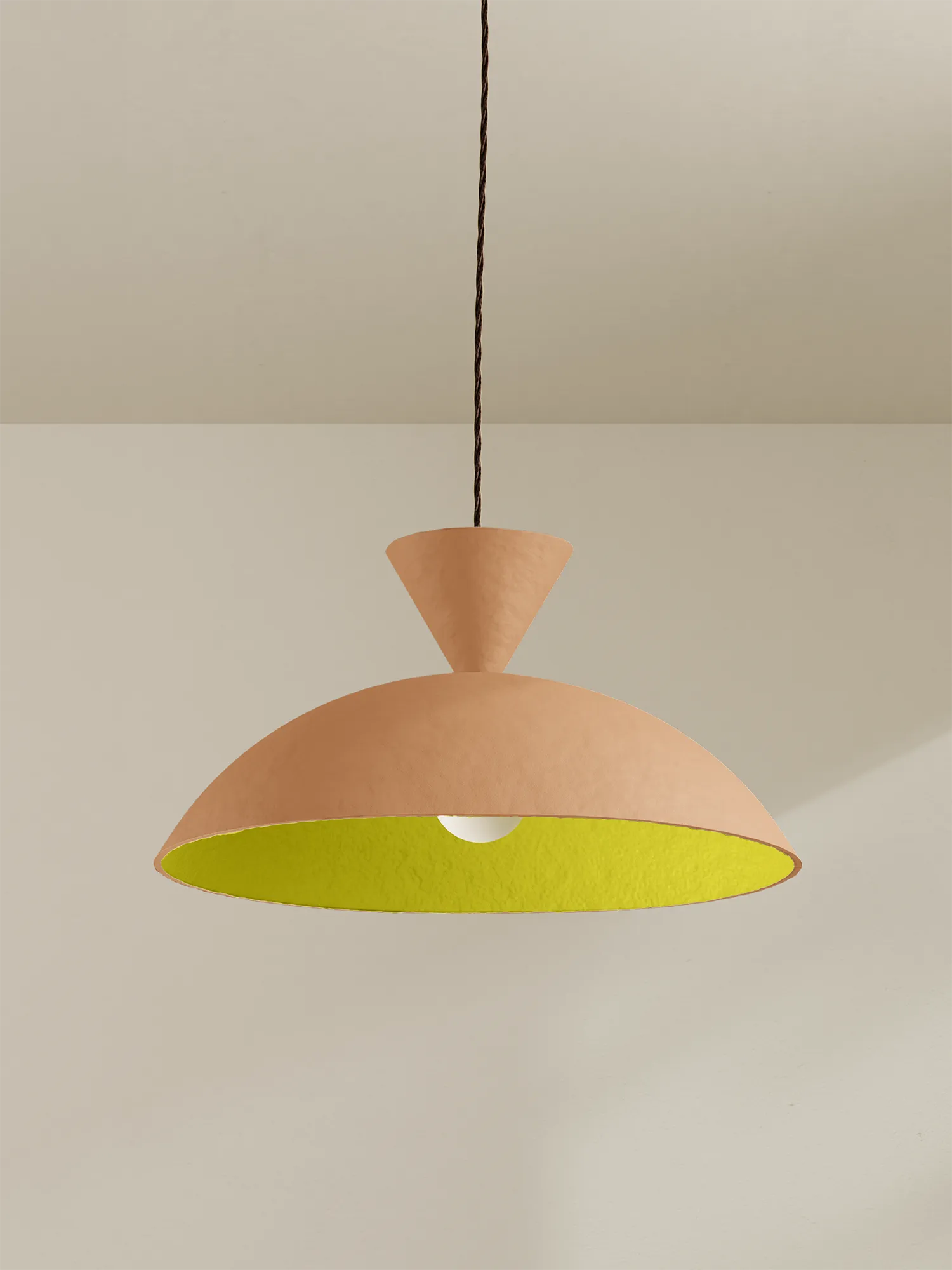 Peach coloured pendant light with a bright yellow interior against a minimalist background.