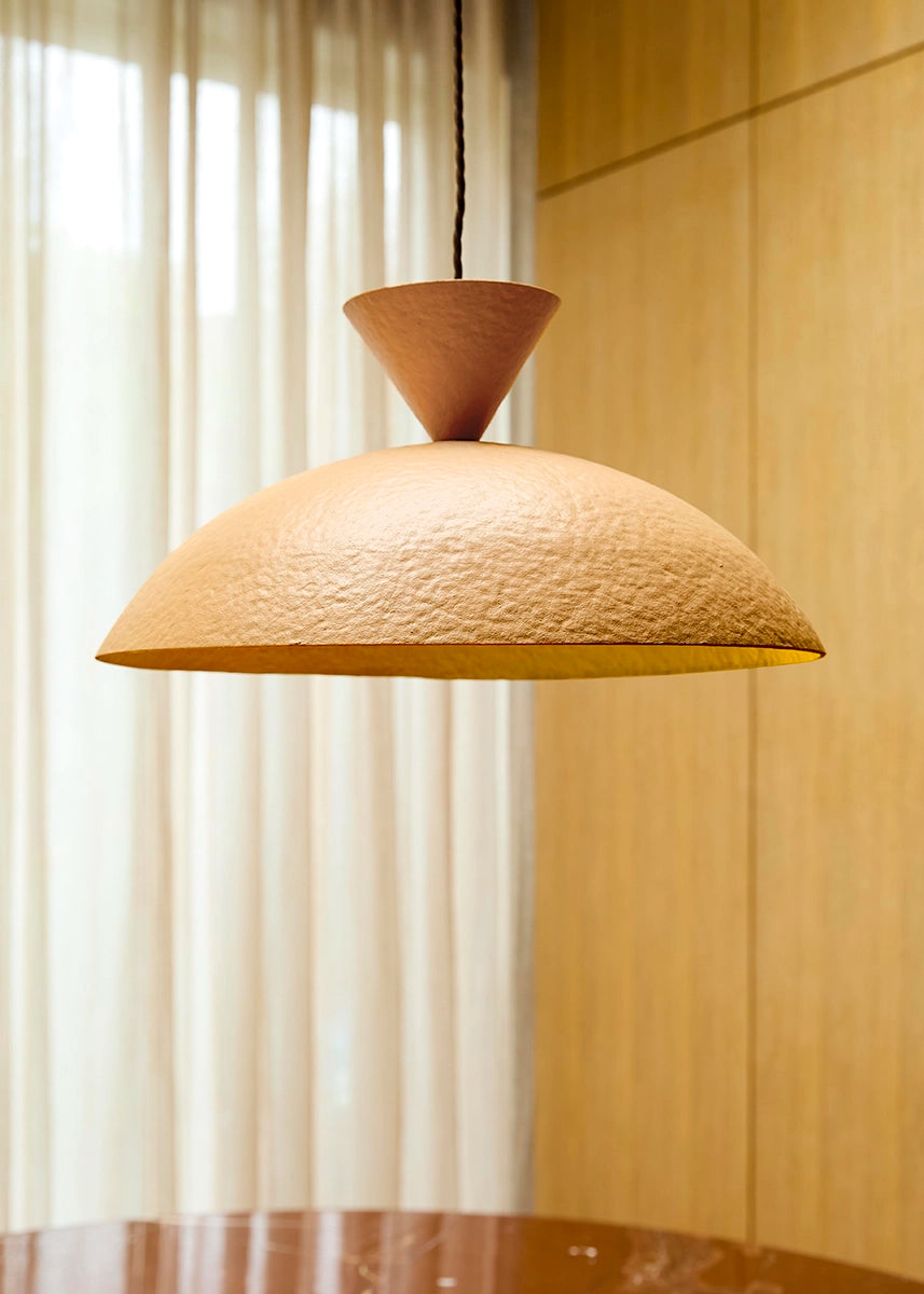 Textured pendant light hanging in a room with curtains and wooden wall.