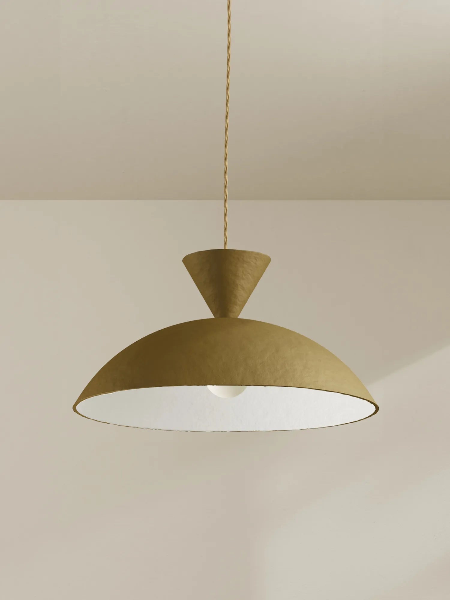 A modern pendant light with a textured green dome shade and a white interior, suspended by a thin beige cord against a neutral wall and ceiling.