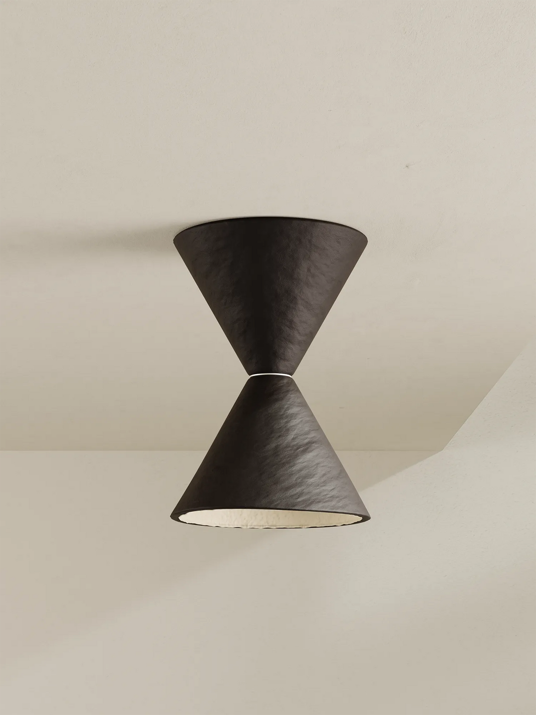 A modern flush mount ceiling fixture with a textured dark brown hourglass design, suspended between two conical shades against a warm off-white ceiling.