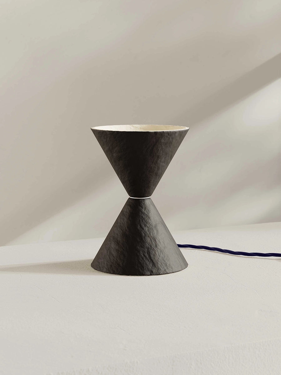 Brown-black table lamp against a neutral background