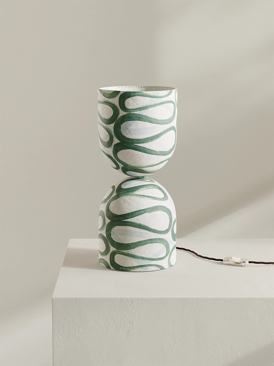 Green and white patterned lamp on a light surface with a neutral background