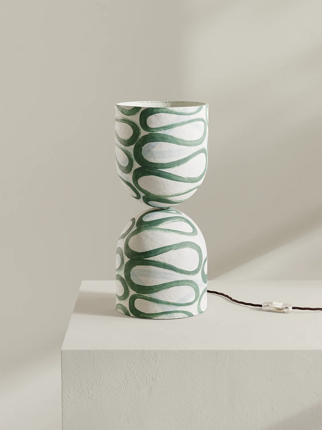Green and white patterned lamp on a light surface with a neutral background