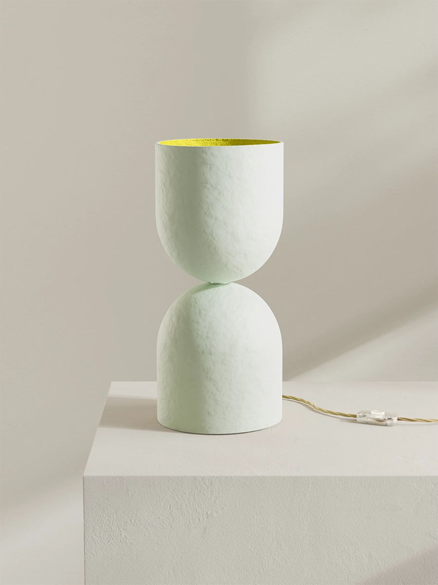 White table lamp with yellow interior on a white pedestal against a beige background