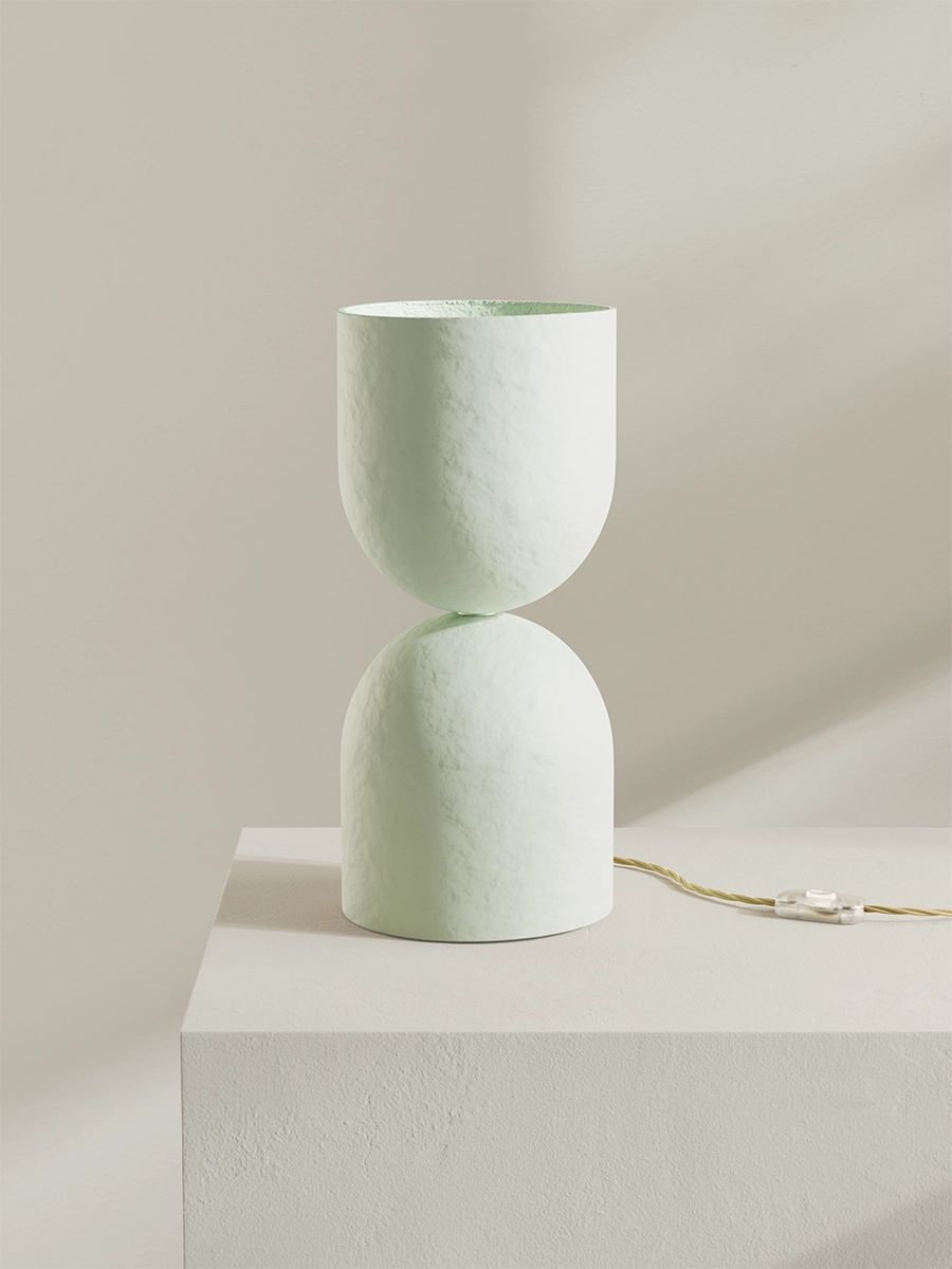 Minimalist white lamp on a light gray pedestal against a beige background