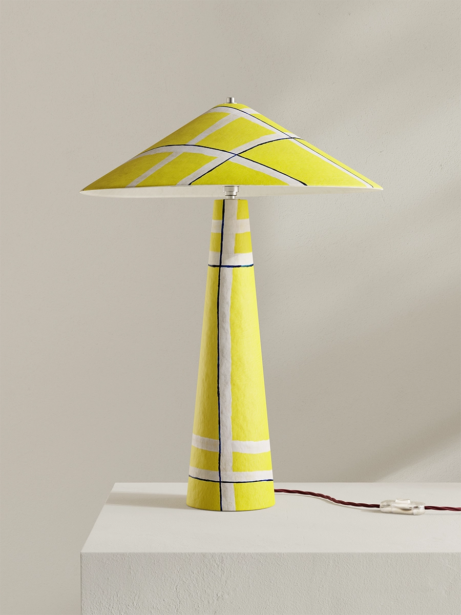 Yellow table lamp with a geometric design on a white surface and light gray background