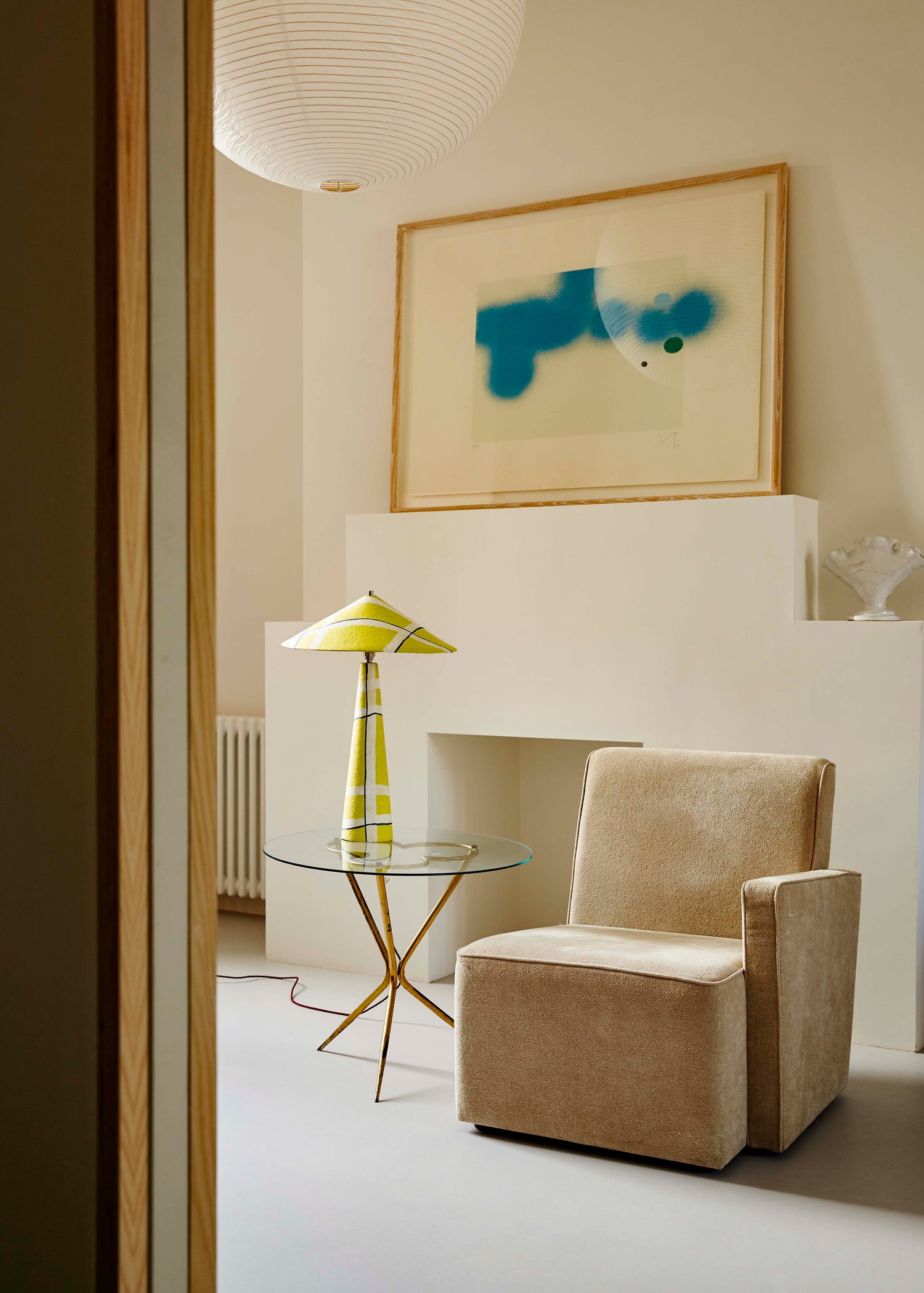 Parasol table lamp in Axis pattern on glass coffee table beside armchair, styled in living room setting